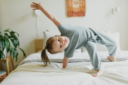 adorable little girl having fun on bed at home