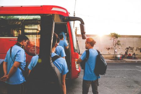 group of men wearing blue shirts about to enter red bus