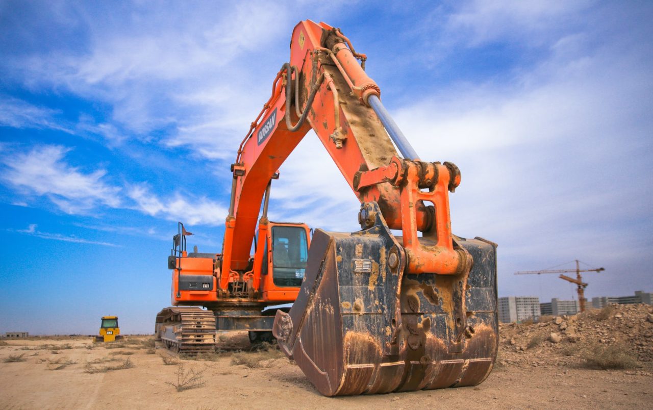 low angle photography of orange excavator under white clouds