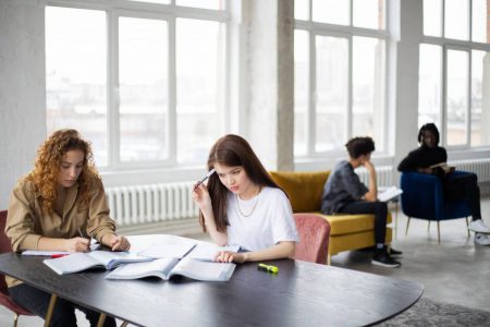 focused students sitting at table and studying in modern workspace
