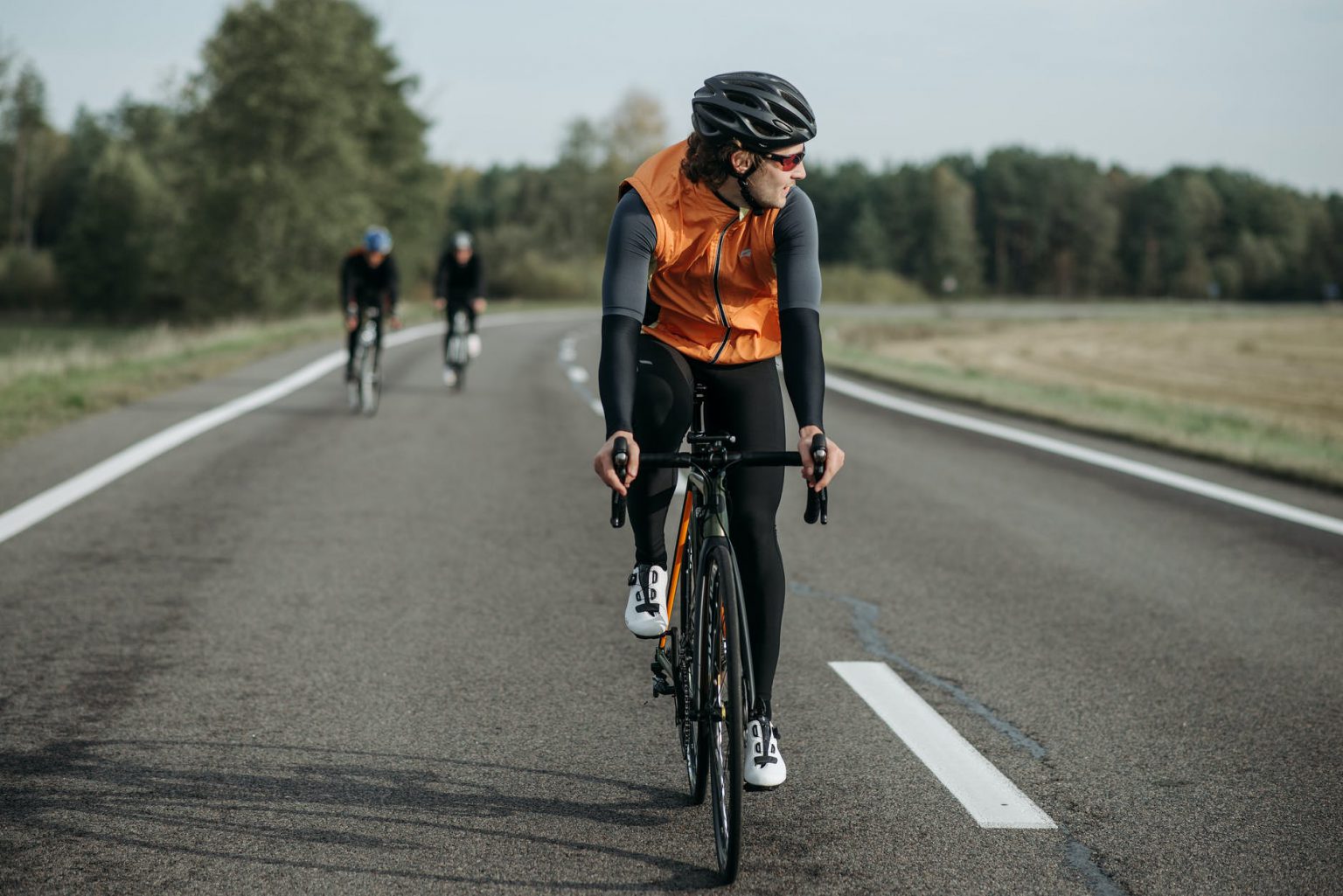 man in orange jacket riding on black bicycle on road